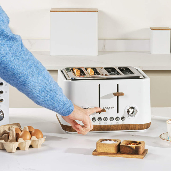 White 4-slice toaster with wooden accents on kitchen counter, hand adjusting controls