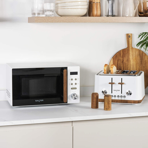 White microwave with door open, hand placing bowl of tomato soup inside