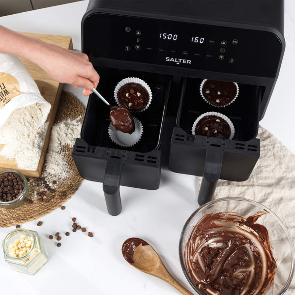 Salter dual air fryer with cupcake batter being spooned into paper cases, top-down view.