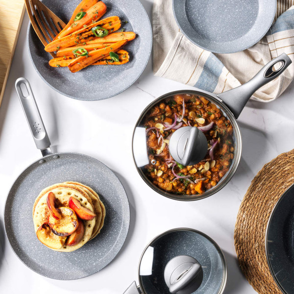 Grey stone-effect cookware set with food, including grilled butternut squash, rice, carrots, pancakes and salmon.