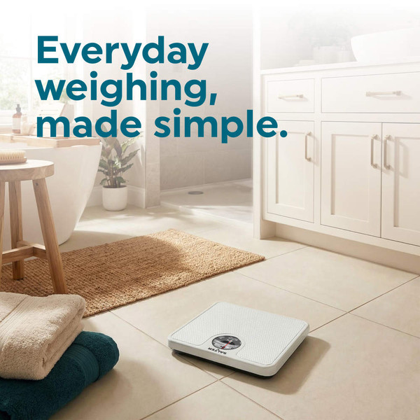 White analogue bathroom scale on tiled floor in modern bathroom setting