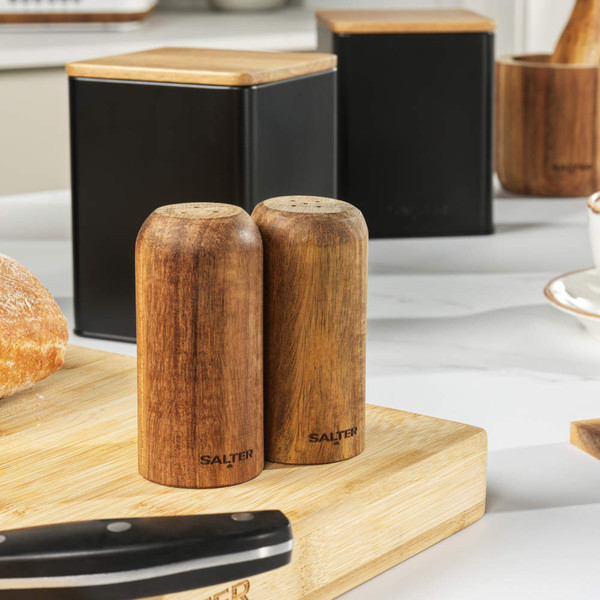 Set of two black metal storage canisters with wooden lids on kitchen worktop
