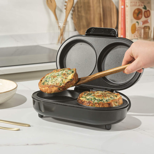 Black dual snack maker open with cooked vegetable muffin being removed