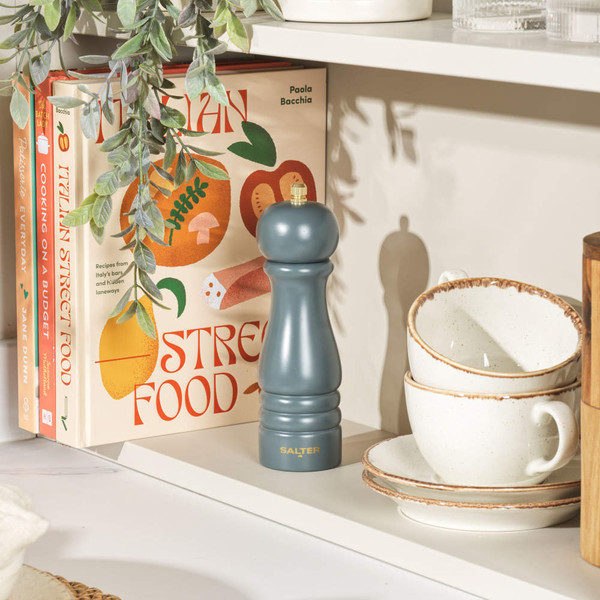 Salter grey pepper mill on kitchen shelf beside cookbooks and stacked cream bowls