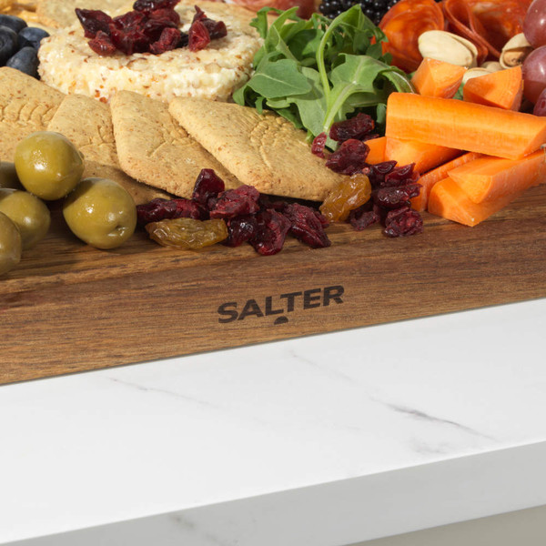 Acacia wood serving board with olives, crackers, vegetables, dried fruit and cheese