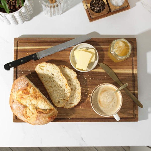 Breakfast scene with sliced sourdough bread, butter, honey, and a cup of coffee on a wooden board