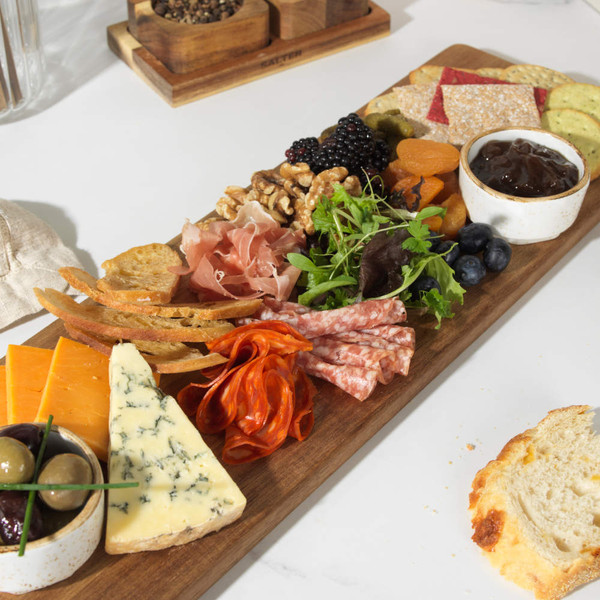 Charcuterie board with assorted meats, cheeses, crackers, olives, fruit and chutney.