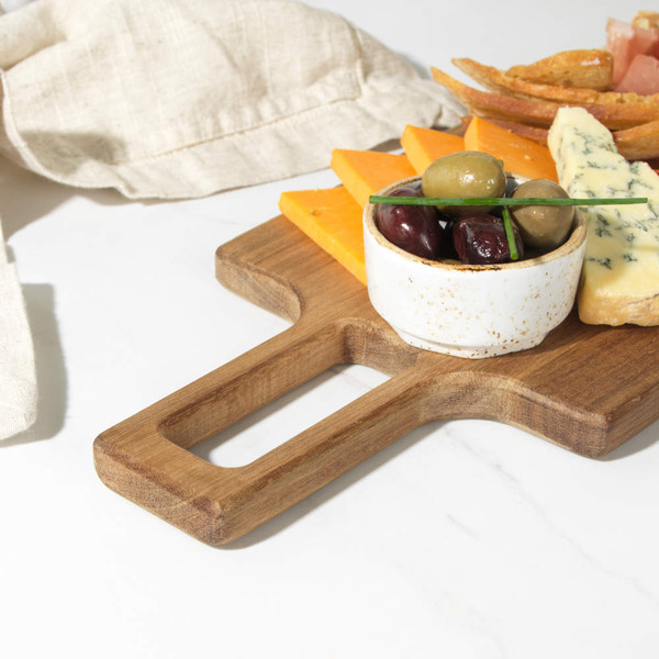 Wooden serving board with cheddar, blue cheese, olives, cured meats, and breadsticks