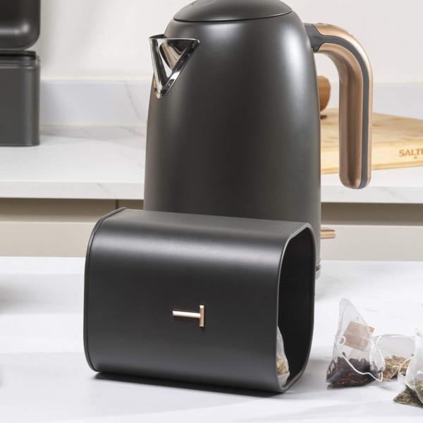 Matte black metal kettle and matching tea caddy with rose gold handle on kitchen counter