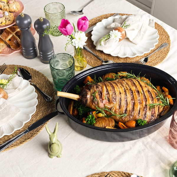 Roast joint in black enamel roasting pan with lid, shown on kitchen worktop