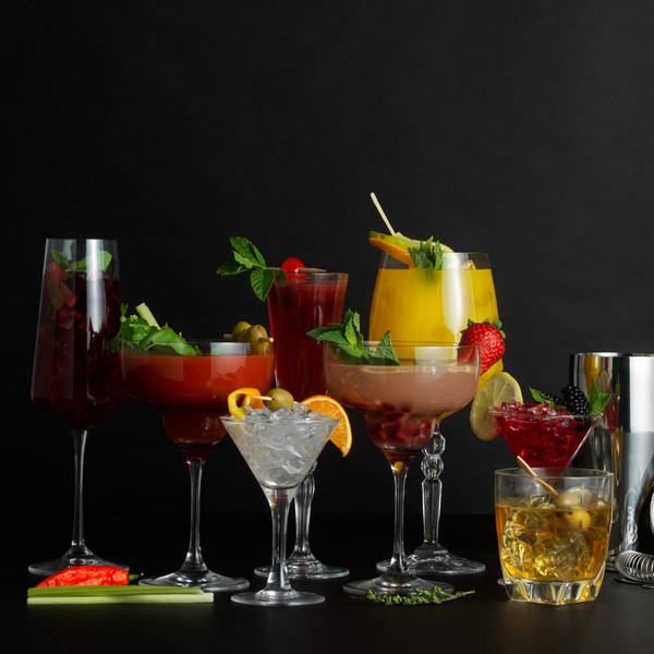 Assorted cocktails in various glasses with fruit and herb garnishes on black background