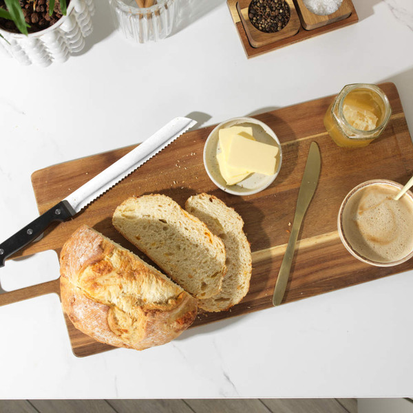 Sliced loaf of bread, butter, honey, coffee and utensils on kitchen worktop