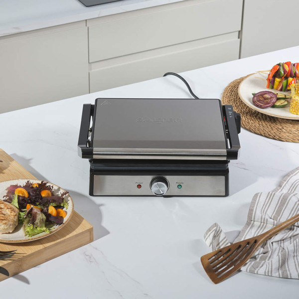 Stainless steel Salter panini grill closed on worktop, with salad and skewers nearby