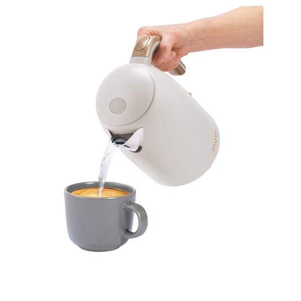 Cream electric kettle pouring hot water into grey mug, shown from side angle.