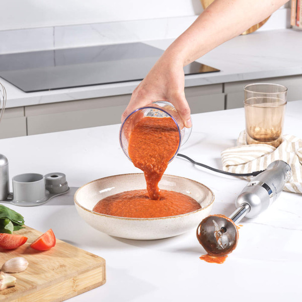 Hand blender with attachments, silver, making tomato soup in modern kitchen