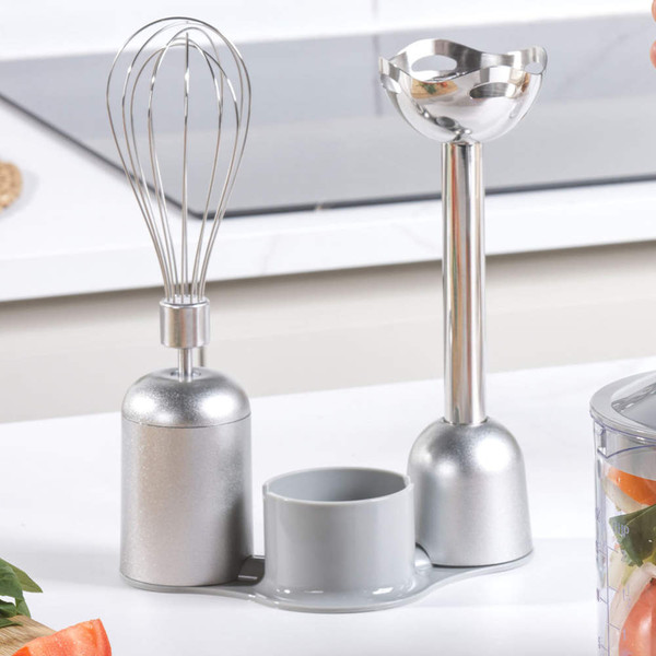 Silver stick blender attachments and stand, shown on kitchen worktop.