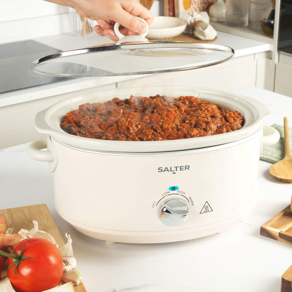 Cream Salter slow cooker on kitchen counter, cooking chilli, hand lifting glass lid