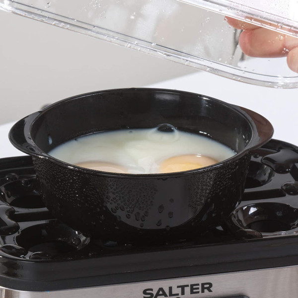 Eggs poaching in black tray inside Salter electric egg cooker, lid being lifted