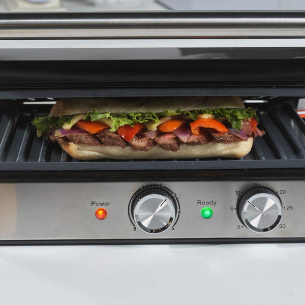 Stainless steel panini press with open grill plates, front-facing controls visible.