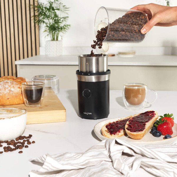 Black electric coffee grinder with stainless steel bowl, shown filled with coffee beans