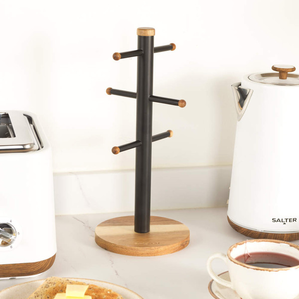 Black and wood mug tree with six pegs for cups, shown on kitchen counter.