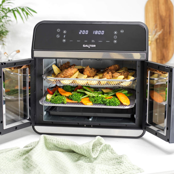 Black Salter air fryer oven on kitchen counter with doors open, showing cooked chicken, chips and vegetables inside