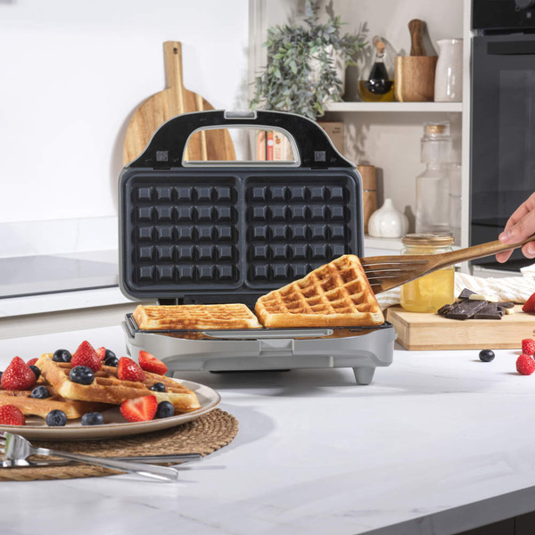 Electric waffle maker with golden waffles, shown in a kitchen setting.