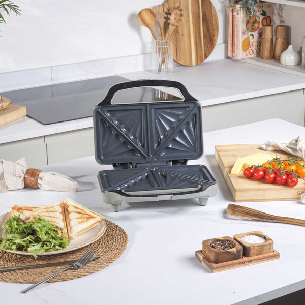 Grey sandwich toaster with two toasted sandwiches on kitchen counter