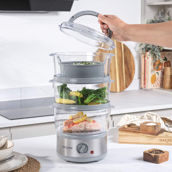 Electric food steamer with salmon and vegetables, hand turning timer dial