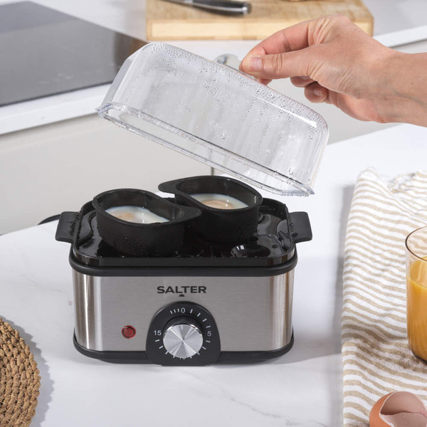 Electric egg cooker with brown eggs, timer dial, and accessories in a kitchen setting