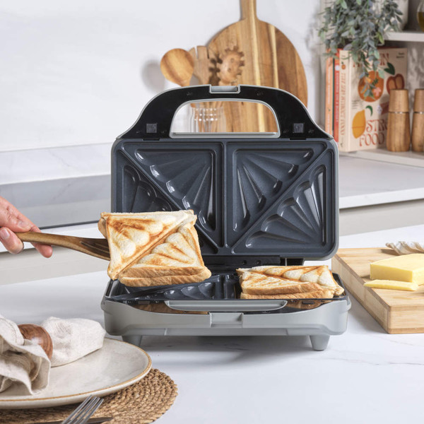 Sandwich maker with two toasted cheese sandwiches in kitchen setting