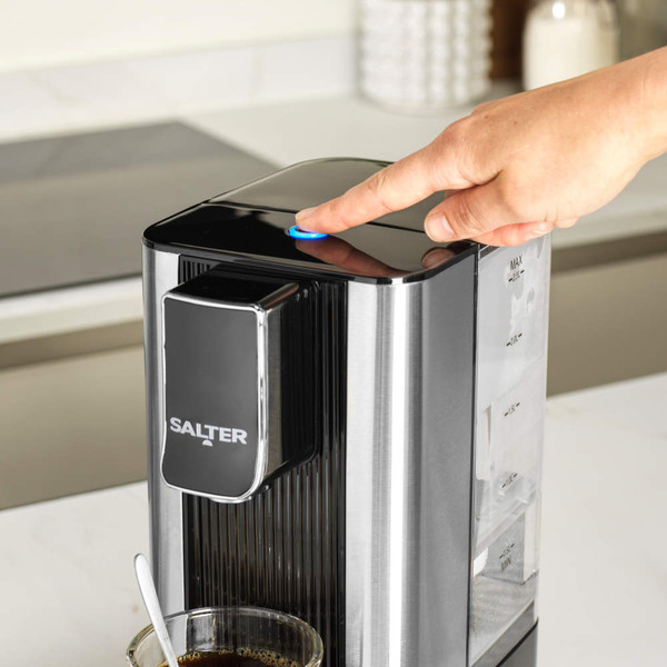 Black Salter hot water dispenser with a hand pressing power button in modern kitchen