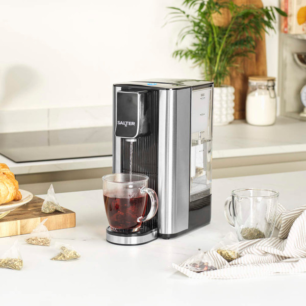 Black Salter hot water dispenser with a hand pressing power button in modern kitchen