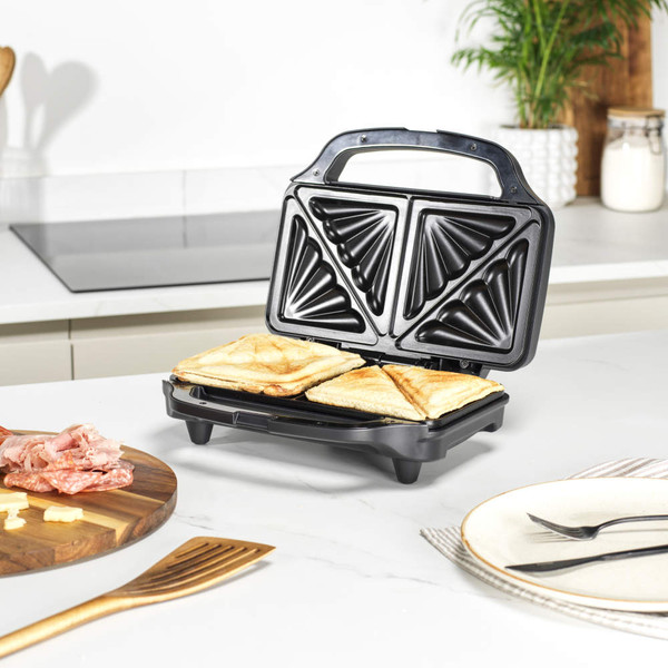 Black sandwich toaster with two toasted sandwiches in a modern kitchen
