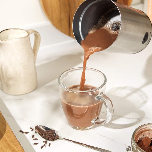 Stainless steel electric milk frother with black handle, shown upright