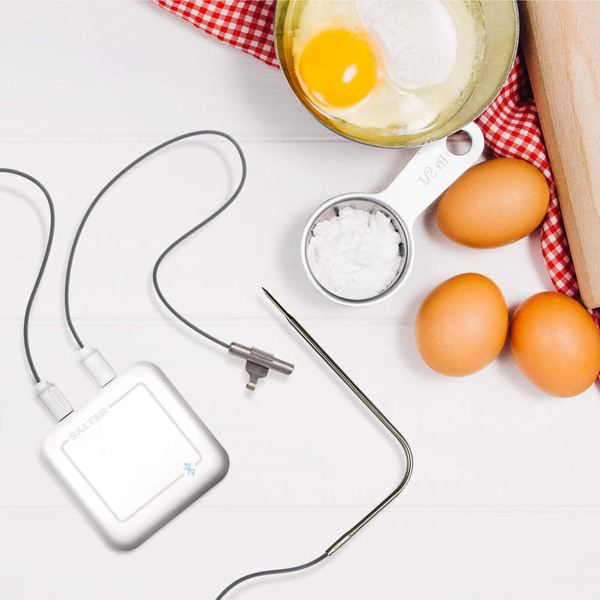 Digital cooking thermometer probe in steak, shown in grill pan
