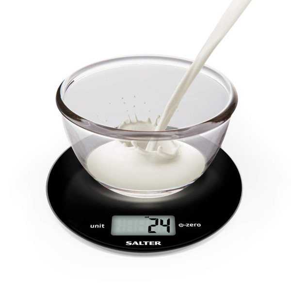 Glass bowl with milk being poured, shown on a black Salter digital kitchen scale.