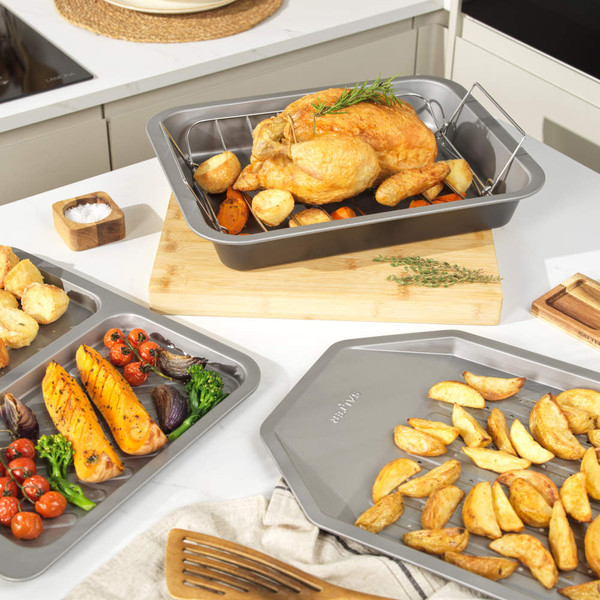 Set of non-stick metal baking trays with British roast foods in modern kitchen