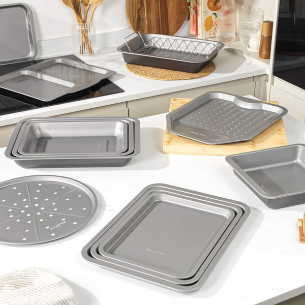 Assorted grey non-stick roasting and baking trays displayed in a modern kitchen