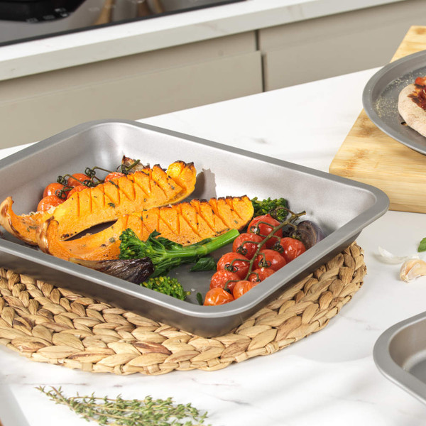 Set of non-stick silver roasting trays and racks on kitchen worktop