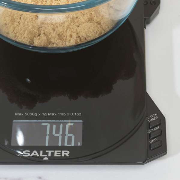 Digital kitchen scale weighing brown sugar in a glass bowl, display shows 746 grams