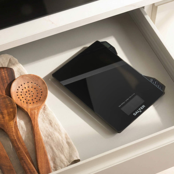 Electronic kitchen scale weighing glass bowl with oil, shown on countertop.