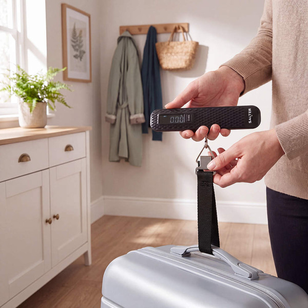 Children with suitcases entering a bright dining room, adult holding device by door.