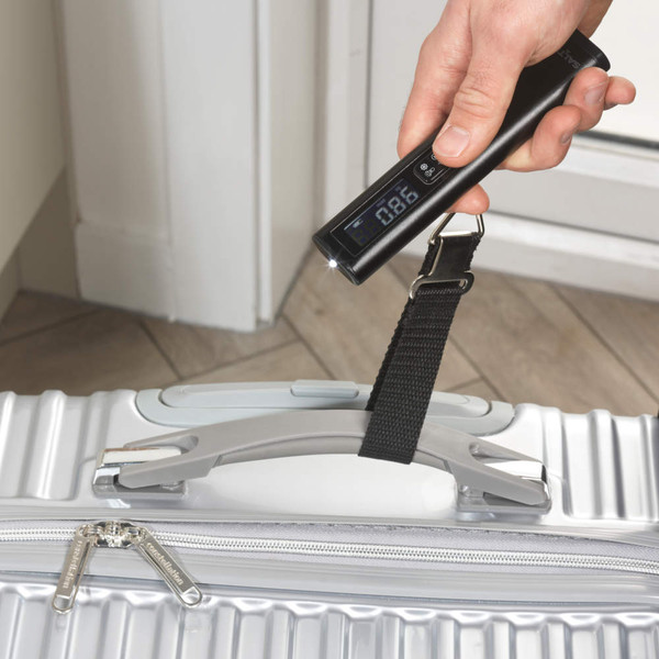 Digital luggage scale weighing silver hard-shell suitcase by the handle