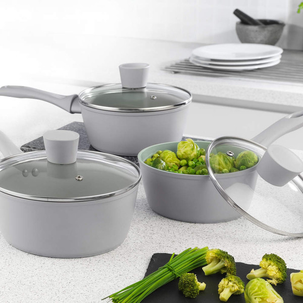 Set of three grey non-stick saucepans with glass lids, shown in a modern kitchen