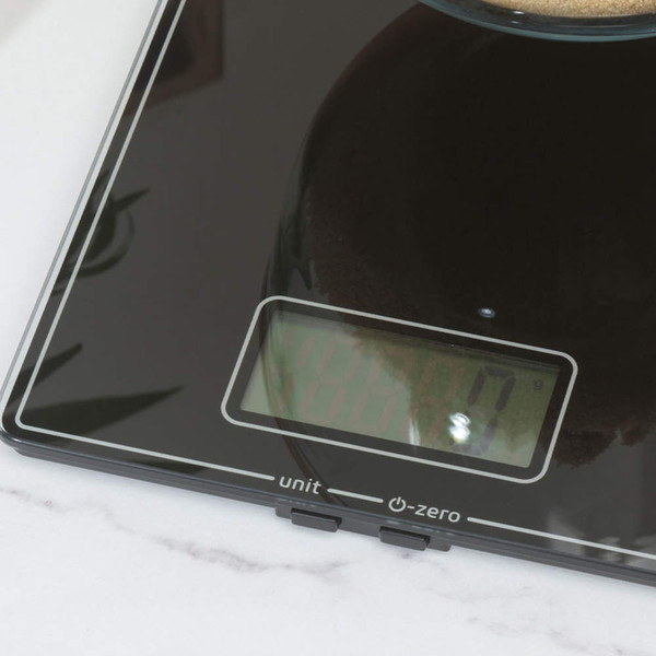 Black digital kitchen scale and wooden utensils in open drawer