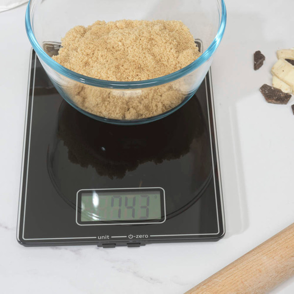 Black digital kitchen scale on worktop, shown with baking ingredients