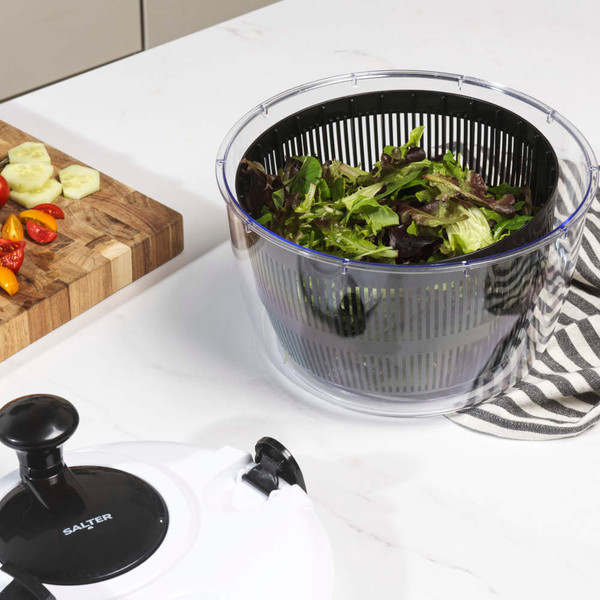 Clear salad spinner filled with mixed lettuce on kitchen counter