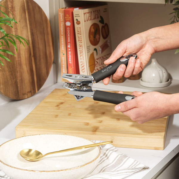 Salter manual can opener with black handles, shown in a modern kitchen setting