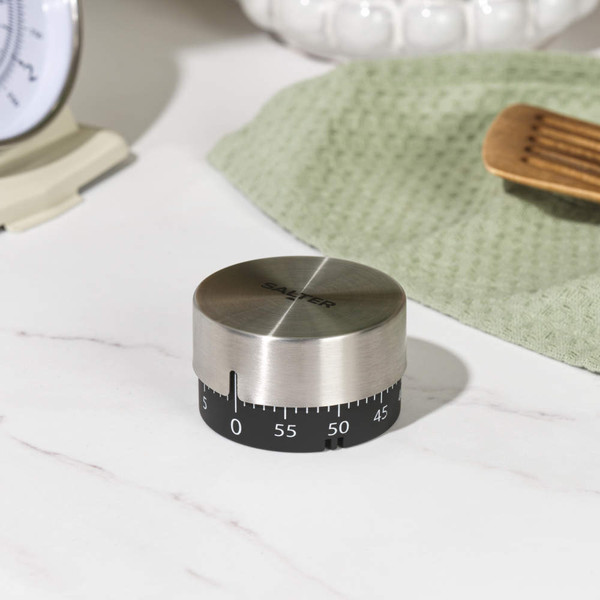 Stainless steel kitchen timer with black dial, shown on a kitchen shelf